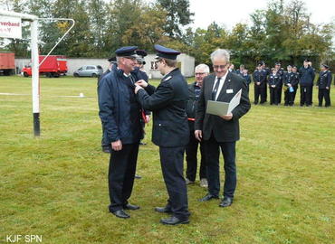 Kreis­jugend­feuerwehrwart Christian Rösiger übergibt Bernd Schulze das Ehrenzeichen der Landesjugendfeuerwehr Brandenburg in Bronze aus.