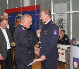 Werner-Siegwart Schippel zeichnet Marcel Bertram (OW Casel) mit Schiedsrichter- und Kampfrichterspange des Deutschen Feuerwehrverbandes in Bronze aus