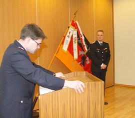 Vorsitzender des Kreis­feuerwehr­verbandes Spree-Neiße e.V. verliest die Urkunde zur Auszeichnung des Kam. Matthias Geigk