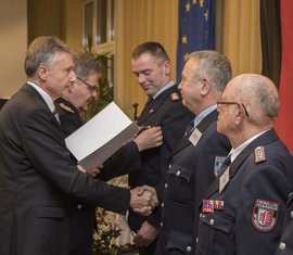 Leiter des Referates 42 des MIK steckt das Ehrenzeichen an die Dienstuniform des Kameraden Thomas Richter (hinten)