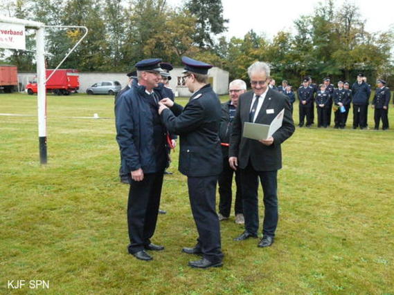 Kreis­jugend­feuerwehrwart Christian Rösiger übergibt Bernd Schulze das Ehrenzeichen der Landesjugendfeuerwehr Brandenburg in Bronze aus.