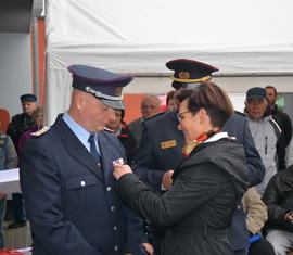 Bürgermeisterin Birgit Zuchold steckt Heino Wochnik die Ehrennadel der Deutschen Jugendfeuerwehr in Gold an.