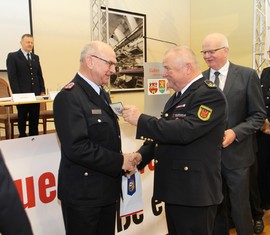 Der Präsident des Landesfeuerwehrverbandes, Werner-Siegwart Schippel, überreicht Siegmund Rückmann das Ärmelabzeichen als Ehrenmitglied