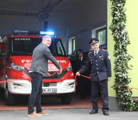Bürgermeister und Ortswehrführer durchtrennen das Band der Fahrzeughalle