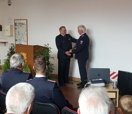 Bernd Frommelt übergibt symbolisch ein Strahlrohr als Staffelstab an seinen Nachfolger Andreas Britze als Standwehrführer der Freiwilligen Feuerwehr Forst (Lausitz)
