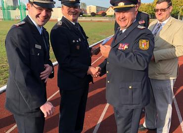 Freudig übergibt Kreisbrandmeister Stefan Grothe (r.) und Vorsitzender Robert Buder (l.) die Schiedsricher- und Kampfrichterspange des Deutschen Feuerwehrverbandes in Silber an Kamerad Matthias Tannert