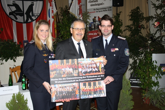 Anja Aldermann und Robert Buder überreichen Landrat Harald Altekrüger (Mitte) eine Collage der Feuerwehr-WM. Als Dank für die Unterstützung der Finanzierung.