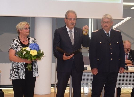 Landrat Harald Altekrüger (Mitte) präsentiert das neue Ärmelabzeichen, das Wolfhard Kätzmer ab Ende Juli tragen wird. Kreistagspräsidentin Monika Schulz-Höpfner (links) gratuliert ebenfalls.