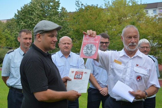 Der Präsident des Landesfeuerwehrverbandes, Rolf Fünning, überreicht das Förderschild an Geschäftsführer Sebastian Schulz