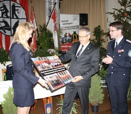 Anja Aldermann und Robert Buder überreichen Landrat Harald Altekrüger (Mitte) eine Collage der Feuerwehr-WM. Als Dank für die Unterstützung der Finanzierung.