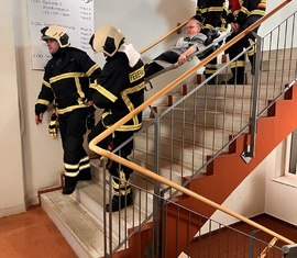 Patient wird durch Feuerwehrkräfte aus der Klinik transportiert bei der Herbstübung in der Klinik Lausitz Forst