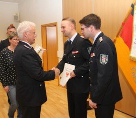 Stadtwehrführer Andreas Britze (links) und der Vorstandsvorsitzende des KFV Robert Buder gratulieren Matthias Geigk